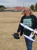Smiling teacher standing in field holding model airplane
